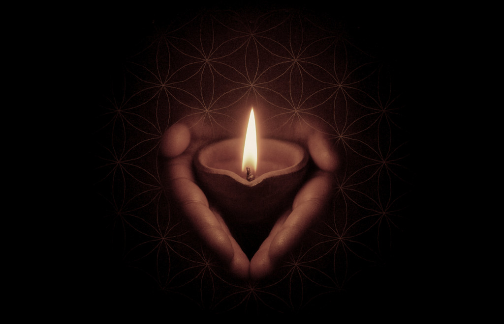 Hands cradling a flame on sacred geometry